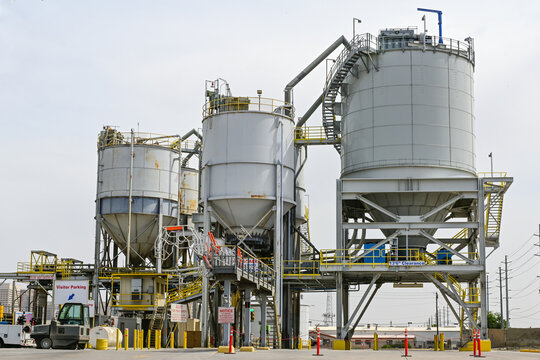 Industrial storage silos and processing equipment at a concrete production plant, representing bulk material storage, batching systems, and construction material manufacturing infrastructure