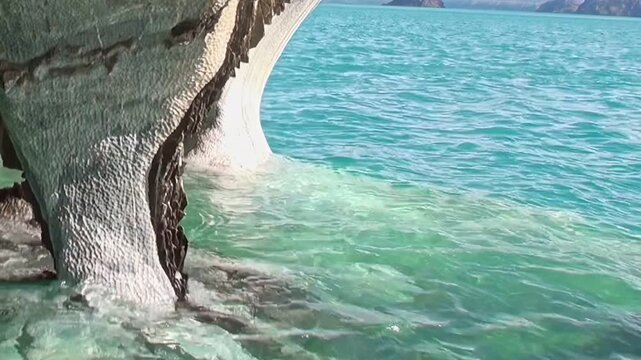 Behold breathtaking Marble Caves of Patagonia. Pristine, emerald waters softly caress unique, smooth marble formations. Peaceful, sunlit moment showcasing General Carrera Lake's natural artistry.