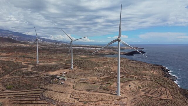 Aerial drone footage of a wind farm in Tenerife, Canary Islands, featuring rows of wind turbines generating renewable energy across a rugged volcanic landscape