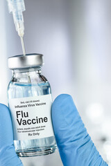 Healthcare concept with a hand in blue medical gloves holding Flu, influenza virus, vaccine vial and syringe needle
