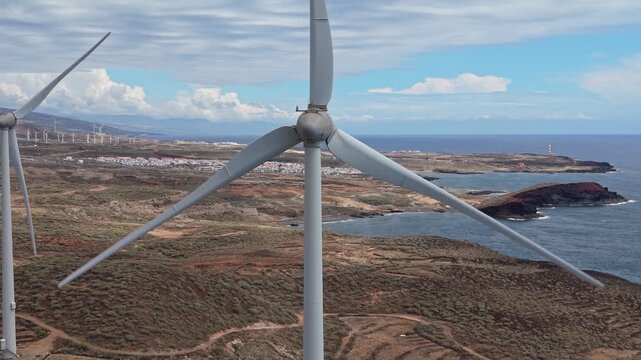 Aerial drone footage of a wind farm in Tenerife, Canary Islands, featuring rows of wind turbines generating renewable energy across a rugged volcanic landscape