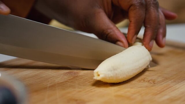 Close up of blogger cutting a banana for fresh chia pudding with yogurt and fruits, chef recording meal prep for a healthy breakfast dish rich in proteins. Woman filming lifestyle video content.