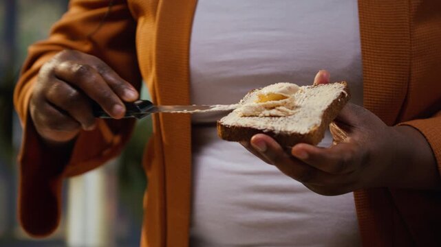 Close up of food vlogger spreading butter cream on a toast slice, preparing a healthy breakfast meal for online audience. Content creator using cheese spread on bread to make avocado dish.
