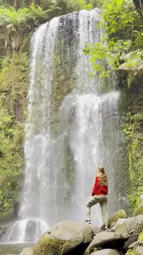 Adventurer girl stands close to and admires the powerful Beauchamp Falls in Great Otway National Park, Victoria, Australia, most beautiful waterfalls located near Melbourne