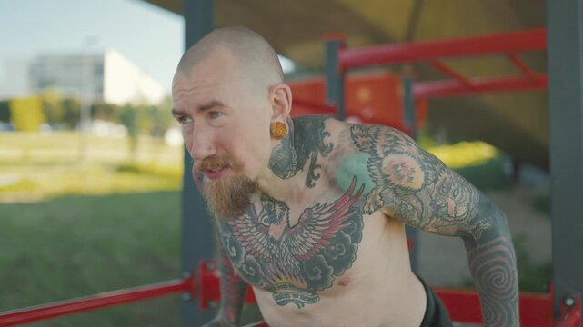 Tattooed athlete doing dips on parallel bars