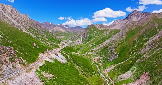 Aerial view of a winding road on steep green mountain slopes, Xinjiang, China.
