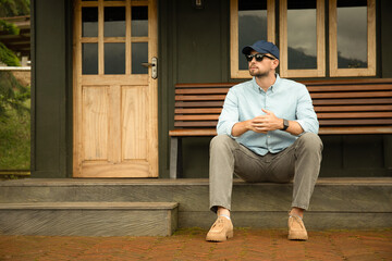 Fototapeta premium A man sits casually on steps outside a house, space for text