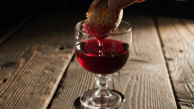 Close-up of hand dipping bread in red wine on wooden table