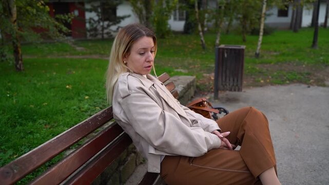 Sad pensive woman , maybe depressed sitting on park bench looking ahead and thinking 