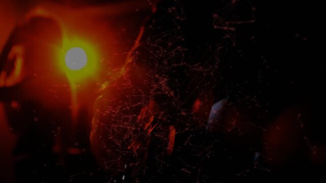 Silhouetted hand moving lamp near particles, illuminating filaments and scattering dust for film