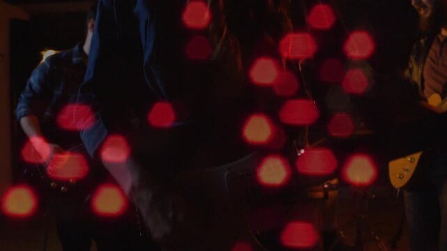 Panning camera revealing vocalist moving to vintage mic singing on stage, guitars, red hex bokeh