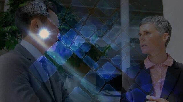 Vertical video: Two colleagues conversing in business atrium, man initiating blue grid showing data