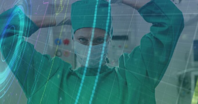 Vertical video: Starting preop surgeon in green scrubs donning mask, tying cap in OR with hologram