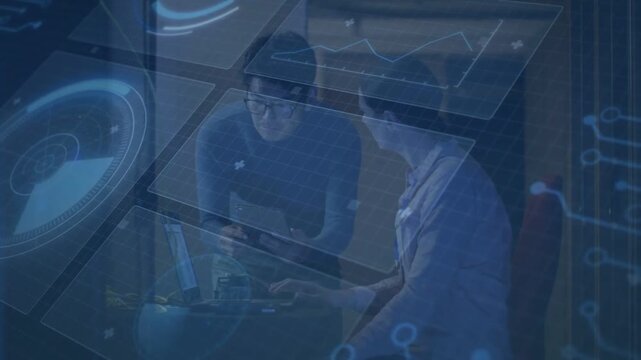 Two coworkers debugging code at desk, right person touching laptop trackpad causing tech UI syncing