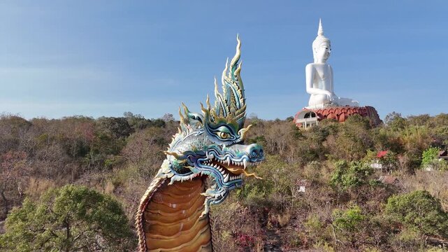 Giant Naga statue and White Buddha on the mountain at Wat Phu Manorom, Mukdahan, Thailand