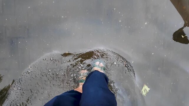 Person walking through shallow flood water in sandals