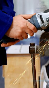 Worker bringing grinder into contact with vise-held metal, producing sparks while smoothing edge