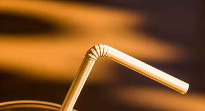 Golden flexible drinking straw macro, metallic bendable straw in warm light, luxury beverage accessory for cocktails and party drinks