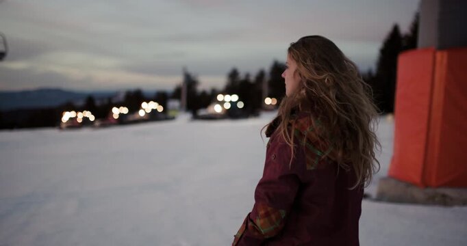 Young Woman Smiles at Dusk on Kopaonik Mountain as Snow Groomers Prepare the Slopes