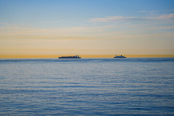 Fototapeta premium Silhouettes of a large cargo ship and a DFDS ferry on the horizon of the English Channel at dusk