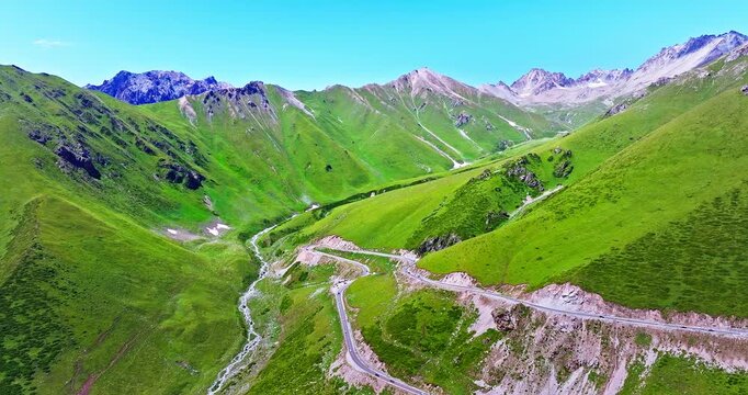 Aerial view of a winding road on steep green mountain slopes, Xinjiang, China.