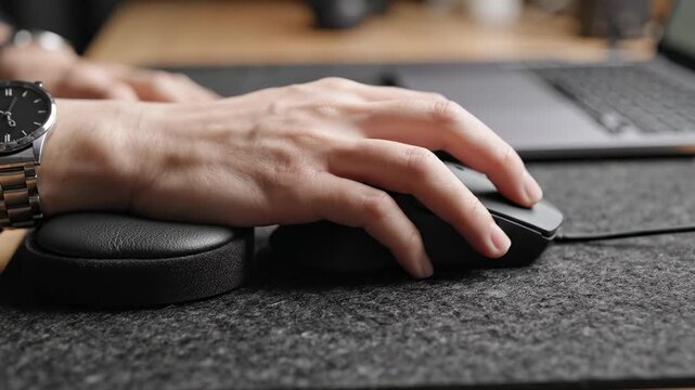 Hand using a computer mouse on desk.