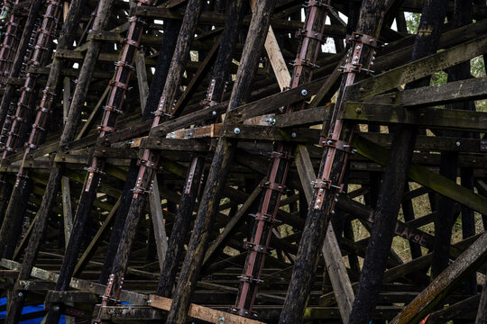 Galvanized iron pole splint, reinforcing metal with collar clamps on old wooden train trestle structural support beams, maintenance and repair patch for added stability and safety
