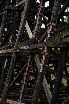 Galvanized iron pole splint, reinforcing metal with collar clamps on old wooden train trestle structural support beams, maintenance and repair patch for added stability and safety
