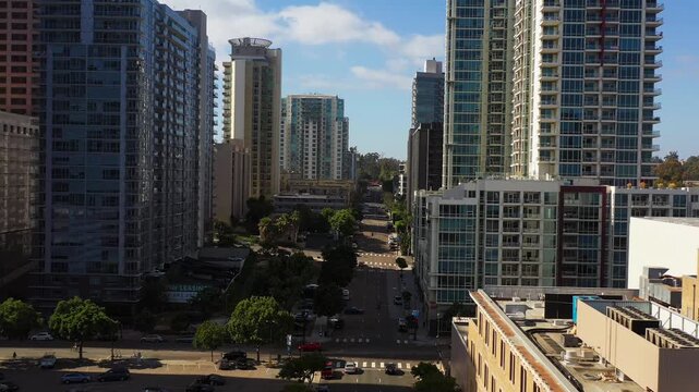 Drone pulling back along 9th Street between buildings in downtown San Diego showing urban architecture and city streets.