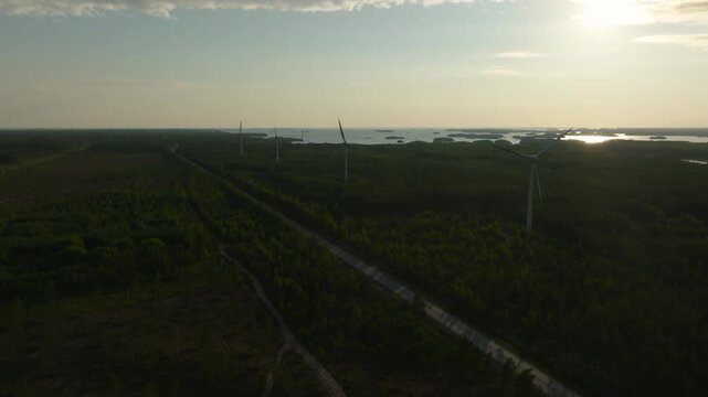 Panoramic drone shot around wind power generators, sunny, summer day in Finland
