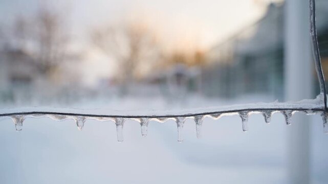 Slow camera movement along ice-covered wire close-up with blurred background