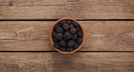 Naklejka premium Wooden plank surface showcasing dried mulberries in bowl and clear copy space