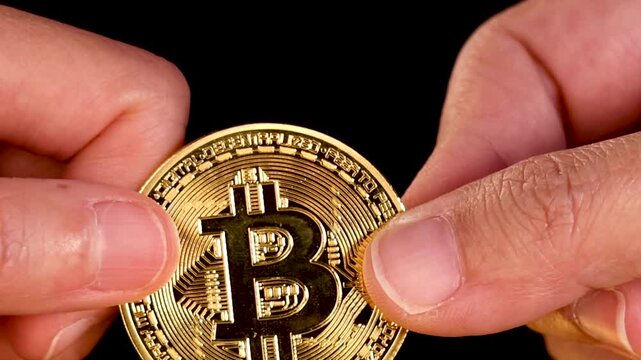 Close Up of Hands Exchanging Gold Bitcoin Coin on Black Background