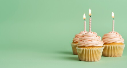 Fototapeta premium Sweet birthday cupcakes with twisted frosting and flickering candles set against a clean green background with copy space