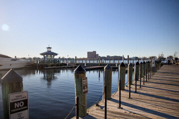 Obraz premium Wooden marina pier with calm water under clear daylight sky