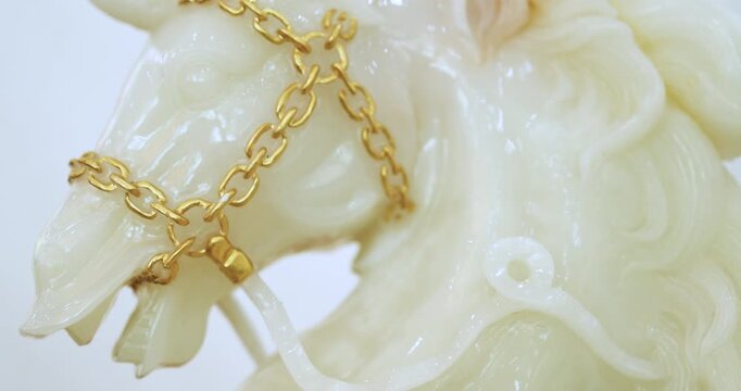 White jade horse sculpture with gold chain on clean background. Luxury and auspicious symbol representing wealth, prosperity and premium lifestyle concept