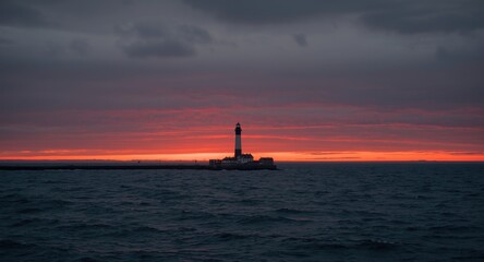Fototapeta premium Sunset backdrop with lighthouse standing tall amidst a gloomy ocean sky
