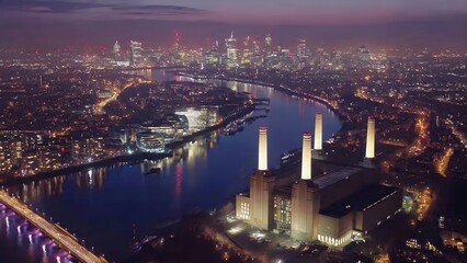 Fototapeta premium Aerial view of illuminated cityscape with river and iconic power station