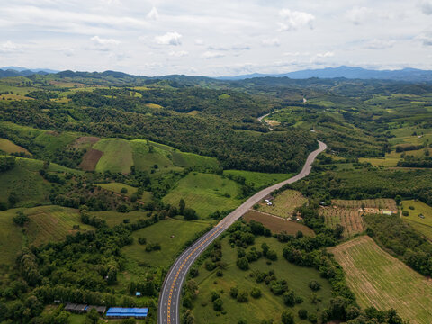 Aerial drone view of Highway winding through lush green mountains between Nan, Thailand. A scenic landscape of the road surrounded by tropical forest and a peaceful countryside