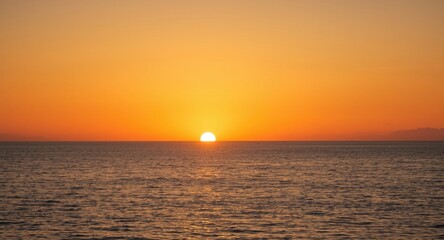 Fototapeta premium Sun nearing horizon with calm ocean foreground