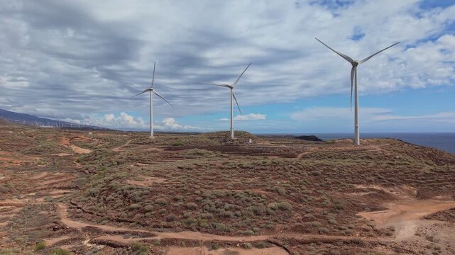 Aerial drone footage of a wind farm in Tenerife, Canary Islands, featuring rows of wind turbines generating renewable energy across a rugged volcanic landscape