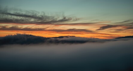 Fototapeta premium Soft swirling mist enveloping an evening sky with antique orange and green colors