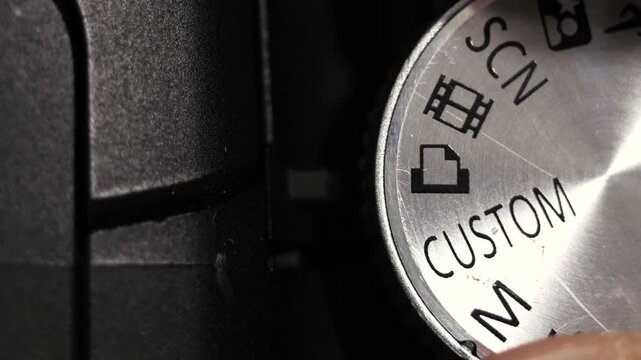 Top down close up of silver mode dial turning on black bridge camera body