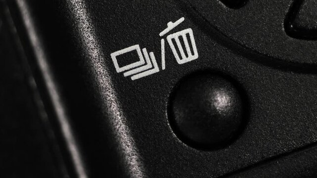 Angled macro view of black button with white trash icon pressed to delete footage