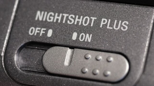 Macro close up of NightShot Plus switch sliding from off to on on black camcorder body