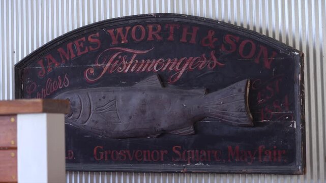 Vintage fishmongers sign with fish relief mounted on wall.