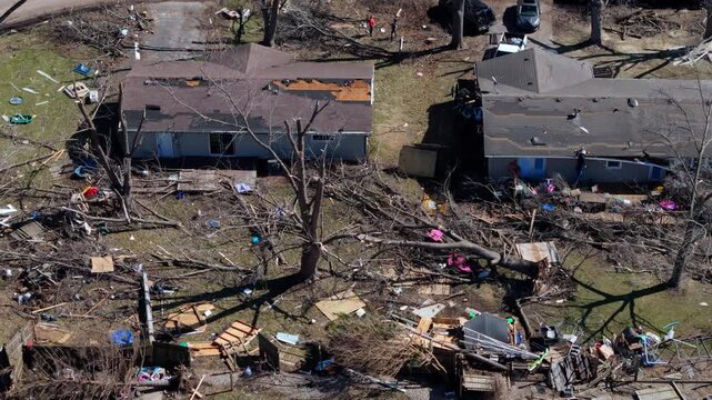 Footage from drone of residential neighborhood destruction after a tornado with damaged houses and scattered debris.