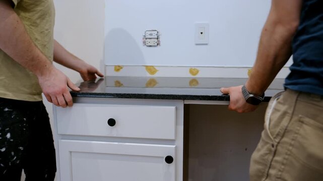 Contractor removes old kitchen countertop during a home renovation project. The worker lifts and detaches the laminate counter, preparing for new installation.