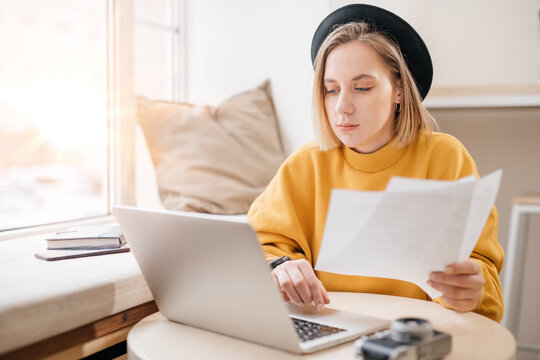 Woman working with papers and on a laptop, typing on keyboard, close up