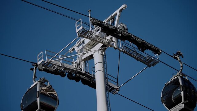 Close-up of a Yokohama Air Cabin ropeway support tower and cable mechanism with gondola passing, showing structural engineering details of the aerial transport system.
